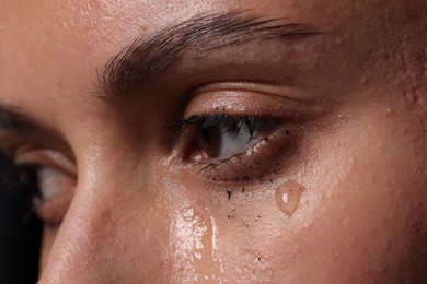 Photo of Sad woman crying on black background, closeup
