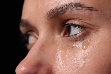 Photo of Sad woman crying on black background, closeup