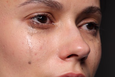 Photo of Sad woman crying on black background, closeup