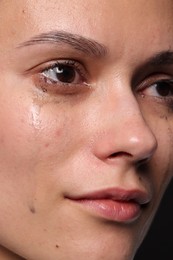 Photo of Sad woman crying on black background, closeup