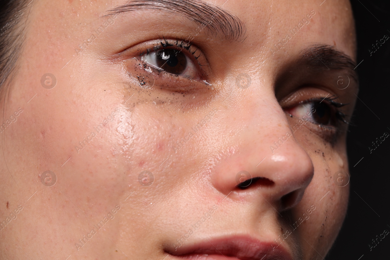 Photo of Sad woman crying on black background, closeup