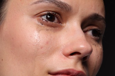 Photo of Sad woman crying on black background, closeup