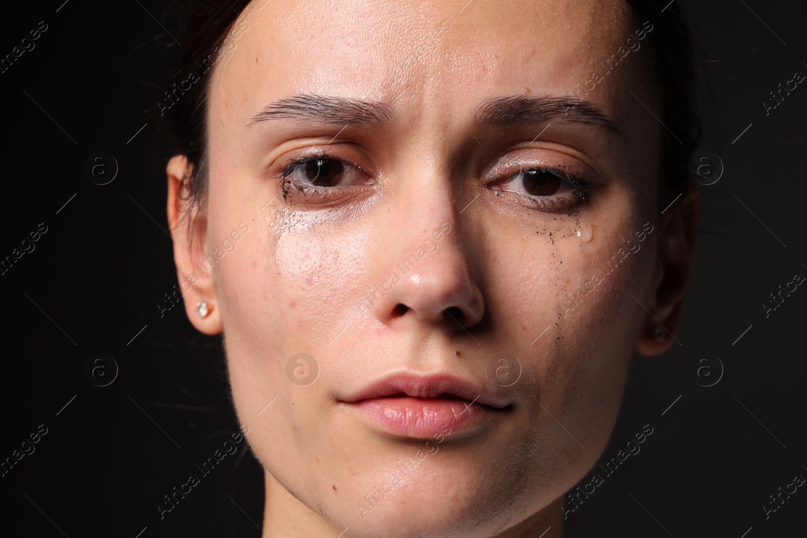 Photo of Sad woman crying on black background, closeup