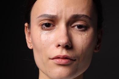 Photo of Sad woman crying on black background, closeup