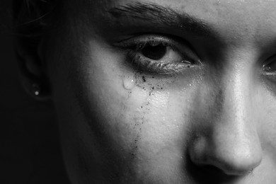 Photo of Sad woman crying on dark background, closeup. Black and white effect