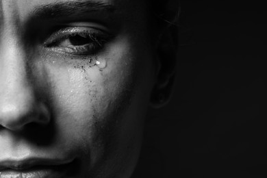 Photo of Sad woman crying on dark background, closeup. Black and white effect