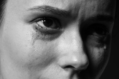 Photo of Sad woman crying on dark background, closeup. Black and white effect