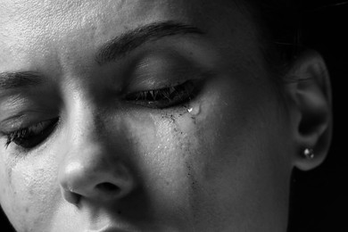Photo of Sad woman crying on dark background, closeup. Black and white effect