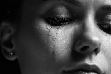 Photo of Sad woman crying on dark background, closeup. Black and white effect