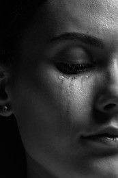 Photo of Sad woman crying on dark background, closeup. Black and white effect