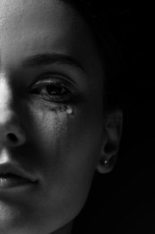 Photo of Sad woman crying on dark background, closeup. Black and white effect