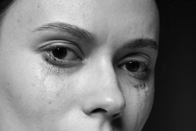 Photo of Sad woman crying on dark background, closeup. Black and white effect