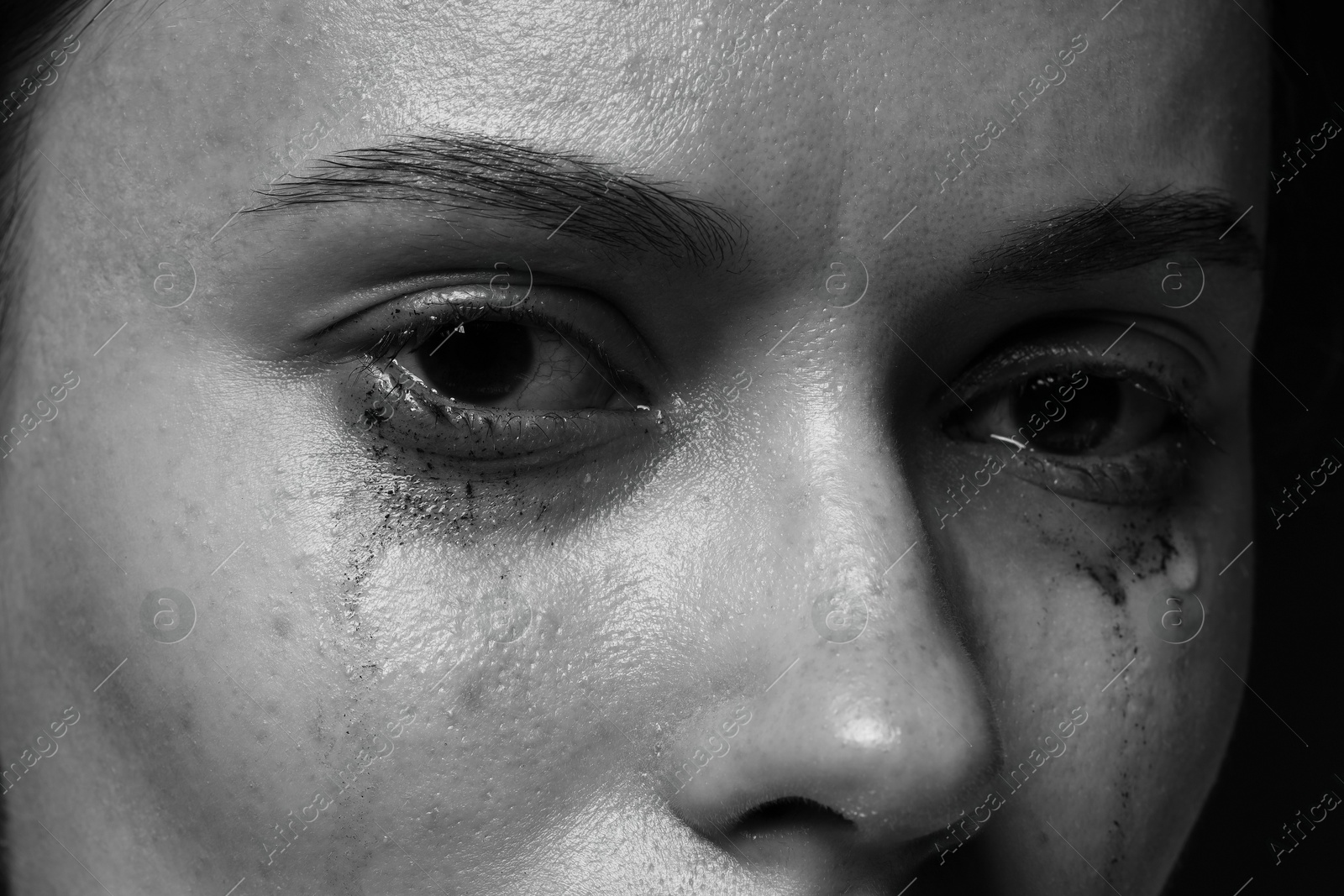 Photo of Sad woman crying on dark background, closeup. Black and white effect