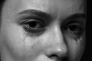 Photo of Sad woman crying on dark background, closeup. Black and white effect