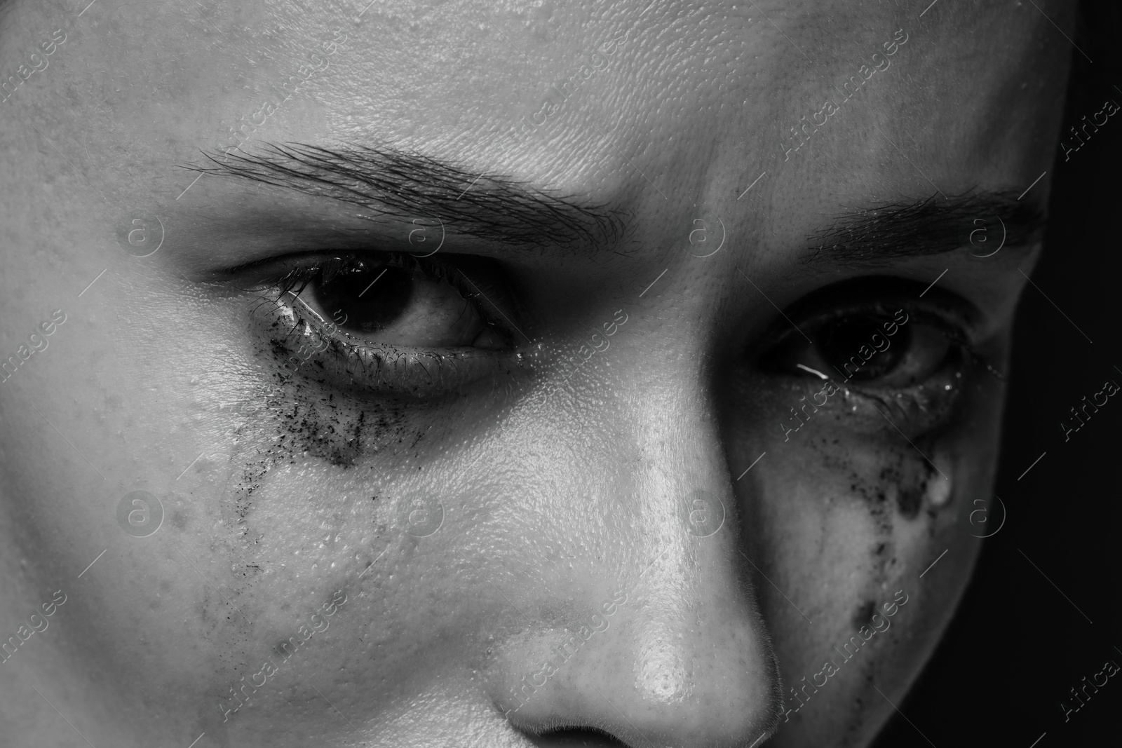 Photo of Sad woman crying on dark background, closeup. Black and white effect