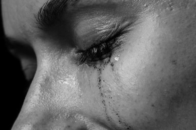 Photo of Sad woman crying on dark background, closeup. Black and white effect