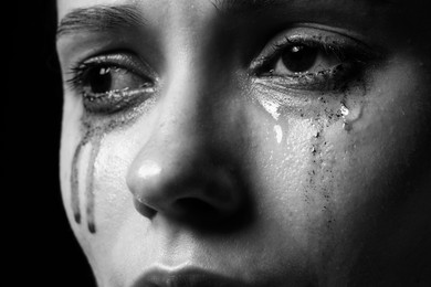 Photo of Sad woman crying on dark background, closeup. Black and white effect
