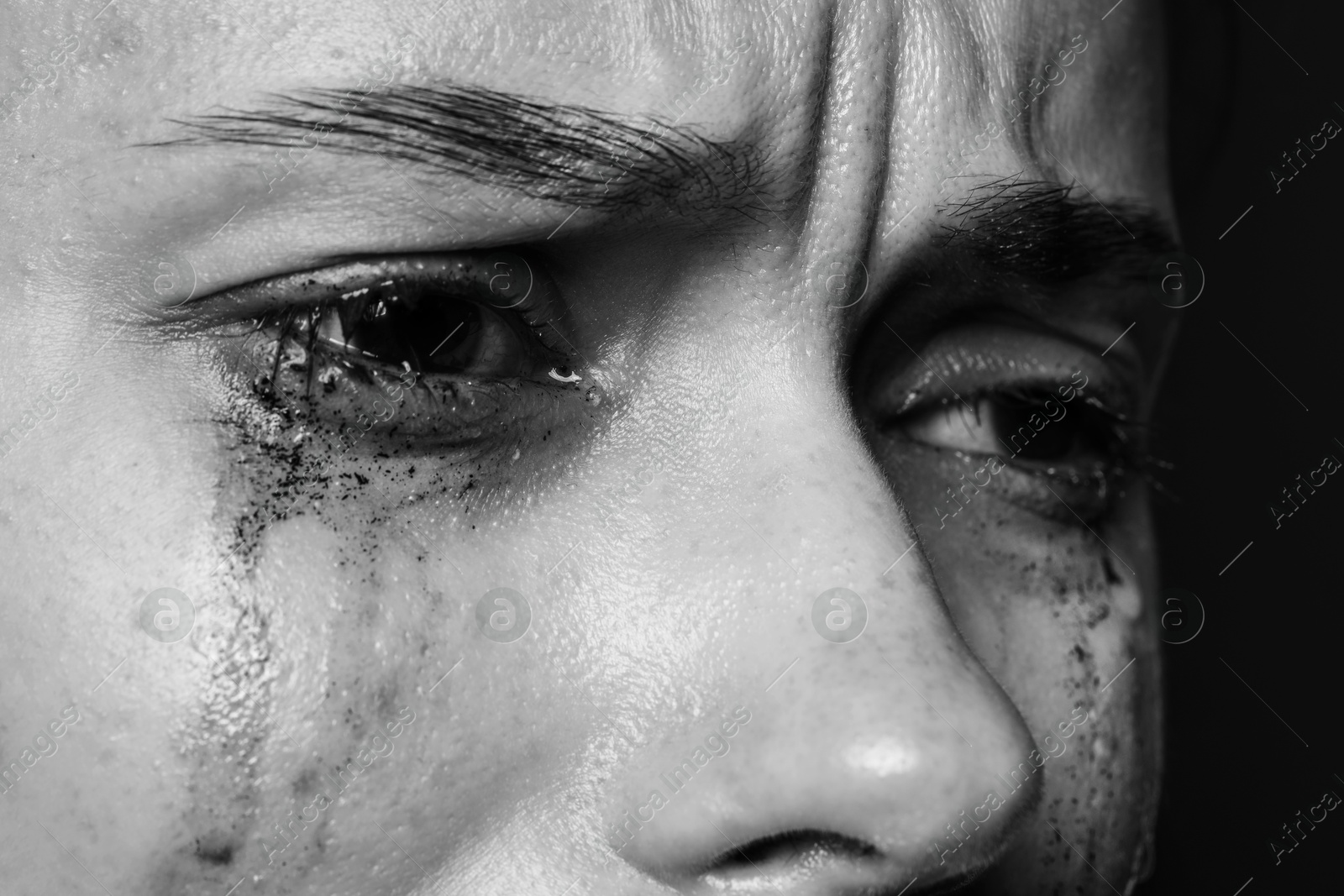 Photo of Sad woman crying on dark background, closeup. Black and white effect