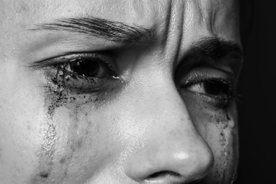 Photo of Sad woman crying on dark background, closeup. Black and white effect