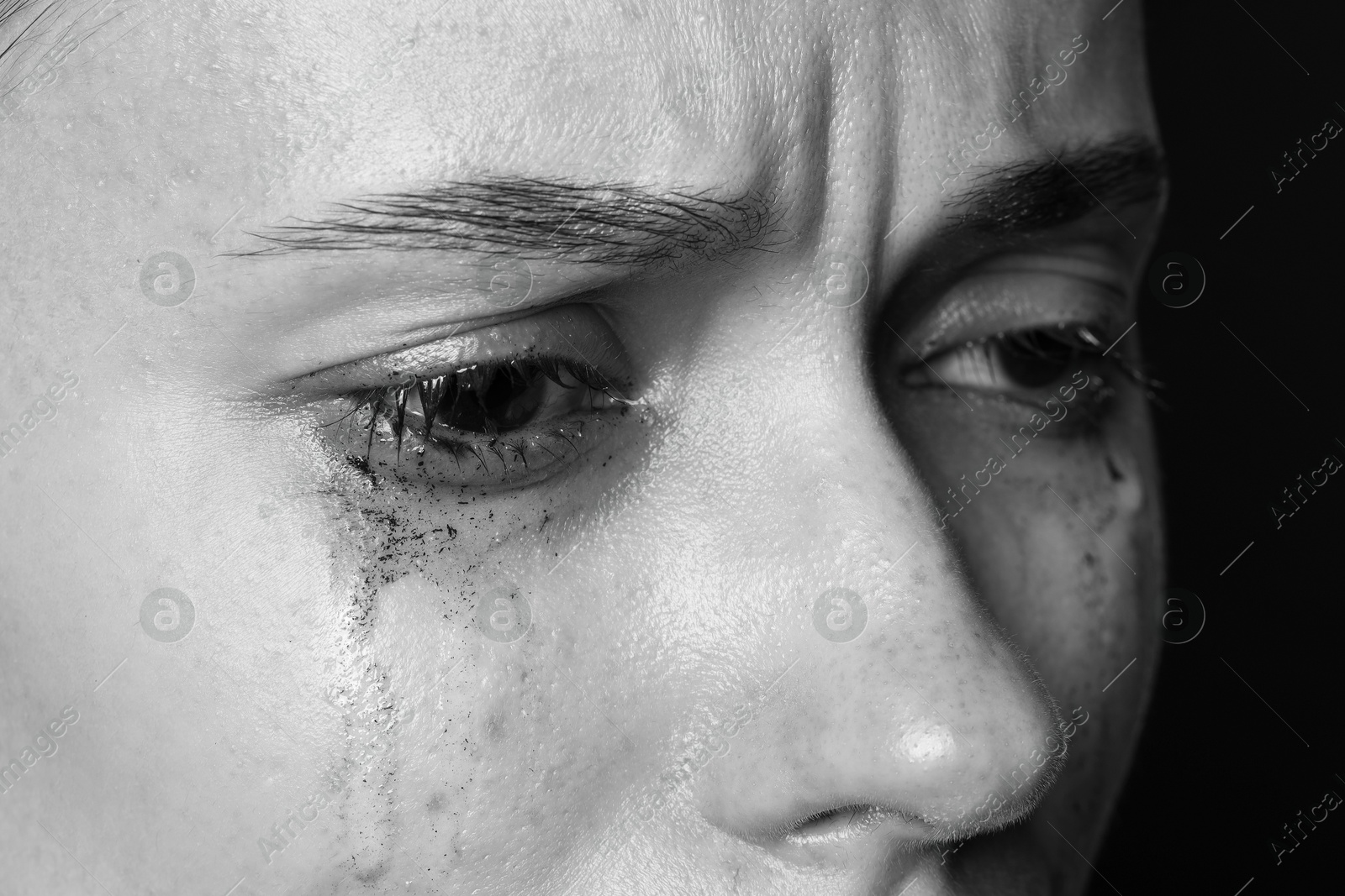 Photo of Sad woman crying on dark background, closeup. Black and white effect