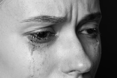 Photo of Sad woman crying on dark background, closeup. Black and white effect