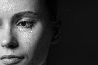 Photo of Sad woman crying on dark background, closeup. Black and white effect