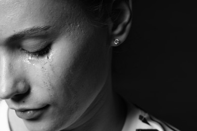 Photo of Sad woman crying on dark background, closeup. Black and white effect