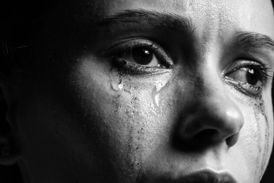Photo of Closeup view of sad young woman crying. Black and white effect