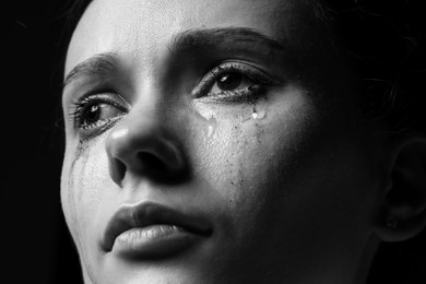 Photo of Sad woman crying on dark background, closeup. Black and white effect