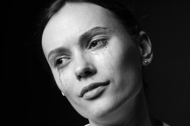 Photo of Sad woman crying on dark background, closeup. Black and white effect