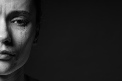 Photo of Sad woman crying on dark background, closeup. Black and white effect