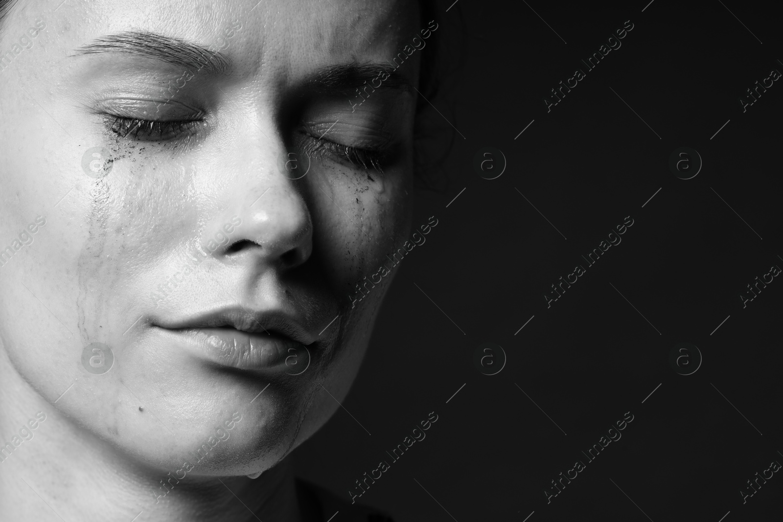 Photo of Sad woman crying on dark background, closeup. Black and white effect