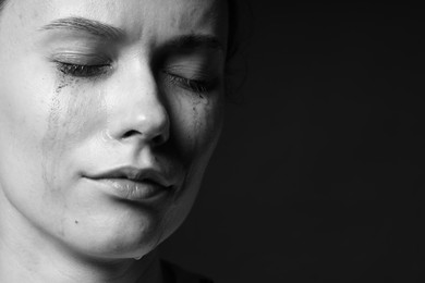 Photo of Sad woman crying on dark background, closeup. Black and white effect