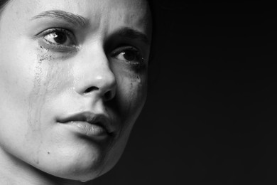 Photo of Sad woman crying on dark background, closeup. Black and white effect