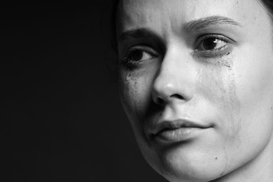Photo of Sad woman crying on dark background, closeup. Black and white effect