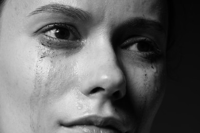 Photo of Sad woman crying on dark background, closeup. Black and white effect