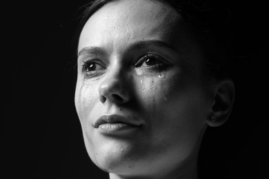 Photo of Sad woman crying on dark background, closeup. Black and white effect