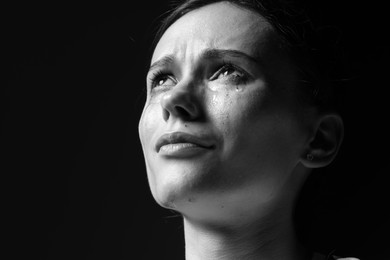 Photo of Sad woman crying on dark background. Black and white effect