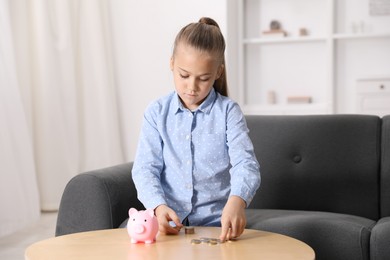 Photo of Little girl counting her pocket money at wooden table indoors