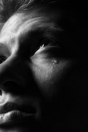 Photo of Sad man crying on dark background, closeup. Black and white effect
