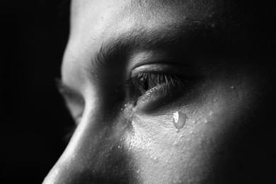 Photo of Sad man crying on dark background, closeup. Black and white effect