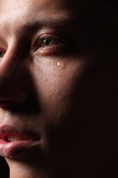 Photo of Sad man crying on black background, closeup