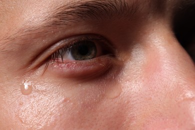 Photo of Closeup view of sad young man crying