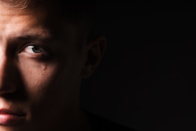Photo of Sad man crying on black background, closeup