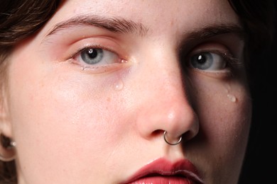 Photo of Sad woman crying on black background, closeup