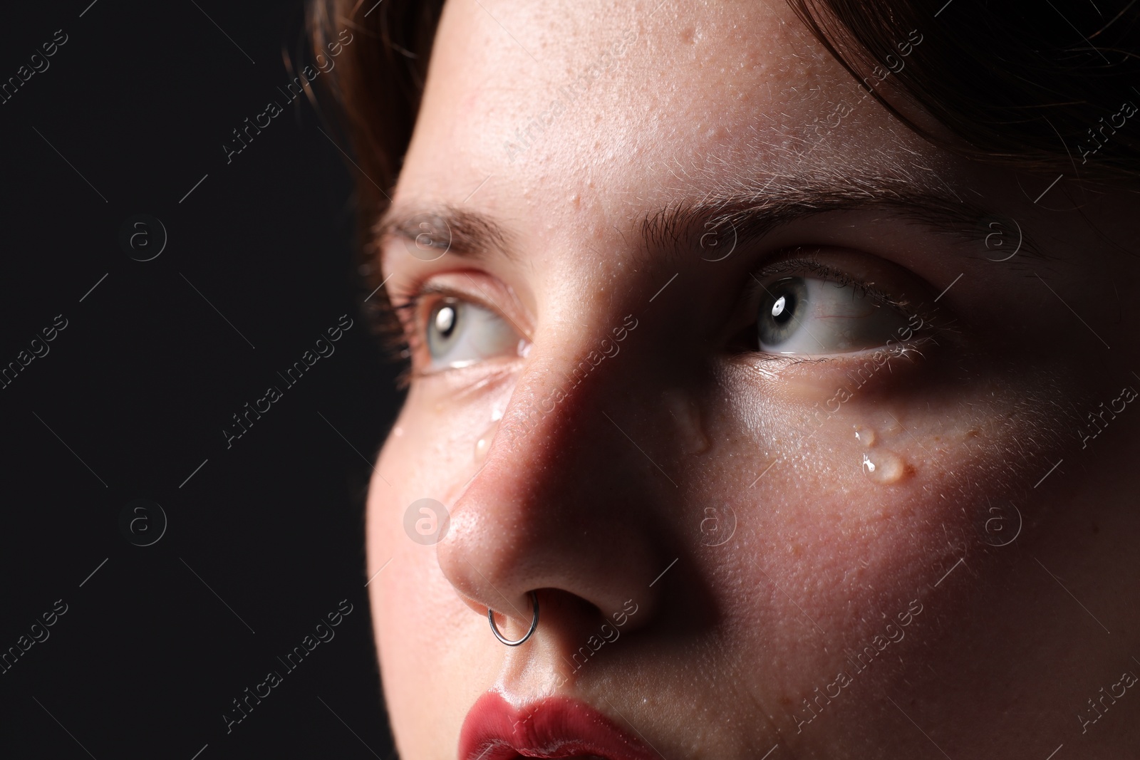 Photo of Sad woman crying on black background, closeup