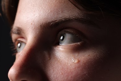 Photo of Sad woman crying on black background, closeup