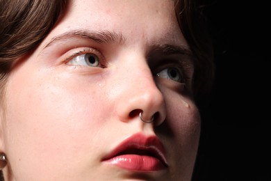 Photo of Sad woman crying on black background, closeup