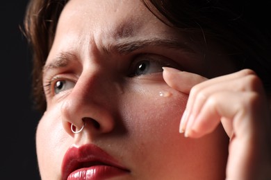 Photo of Sad woman crying on black background, closeup