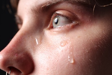 Photo of Sad woman crying on black background, closeup